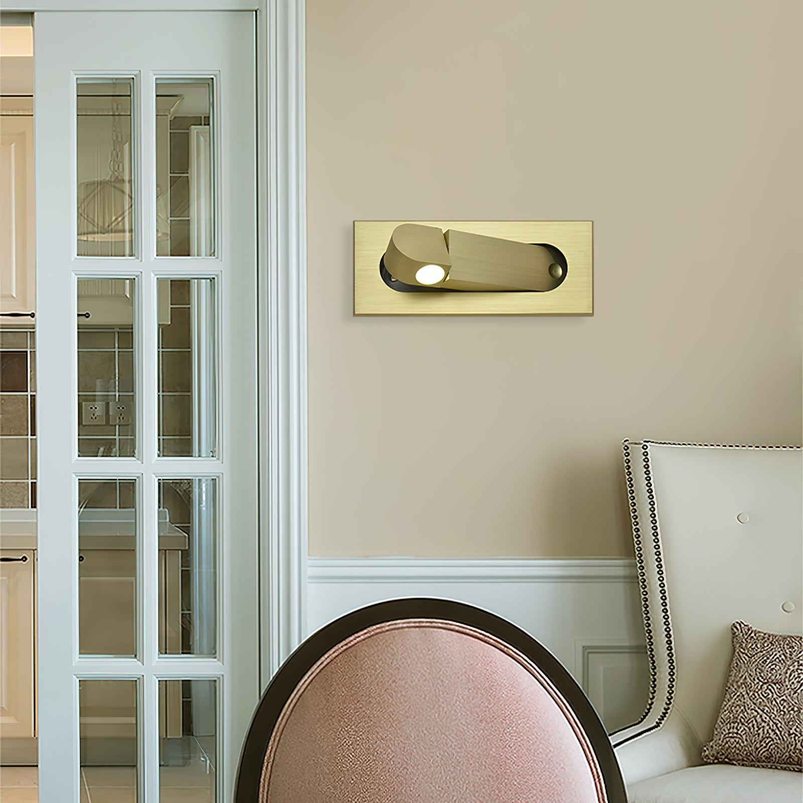 Gold wall light fixture on a beige wall next to a white door with glass panels.