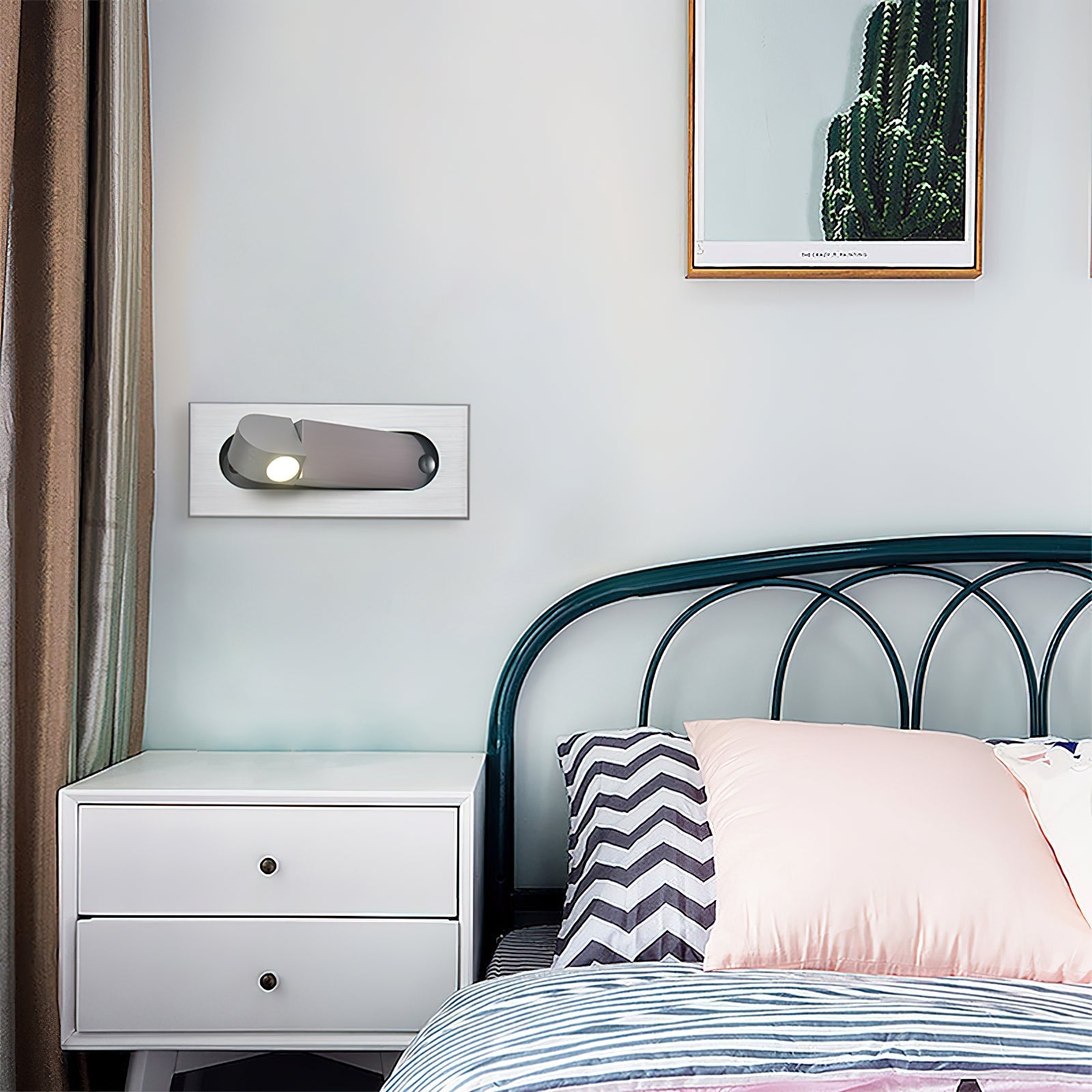 Bedroom with a bed featuring striped bedding and pillows, a white nightstand, and a framed cactus picture on the wall.
