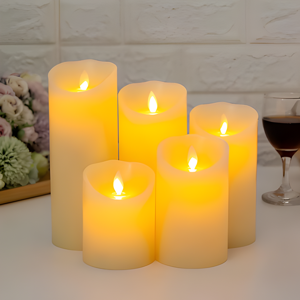 Set of five lit candles on a table with a glass of red wine and flowers in the background.