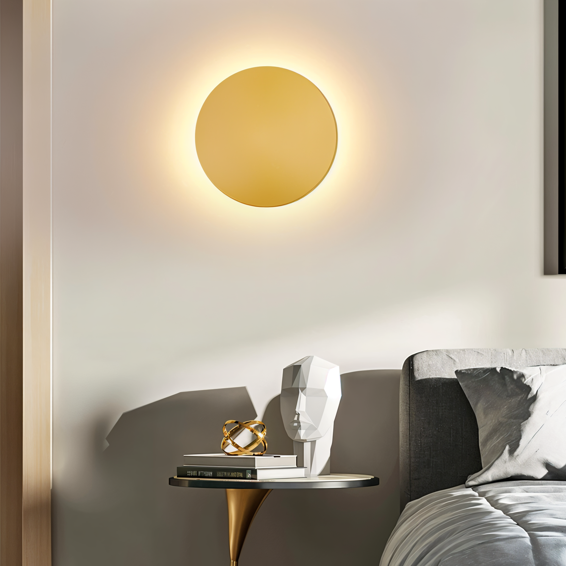 Modern wall lamp with a gold finish on a neutral wall above a bed.