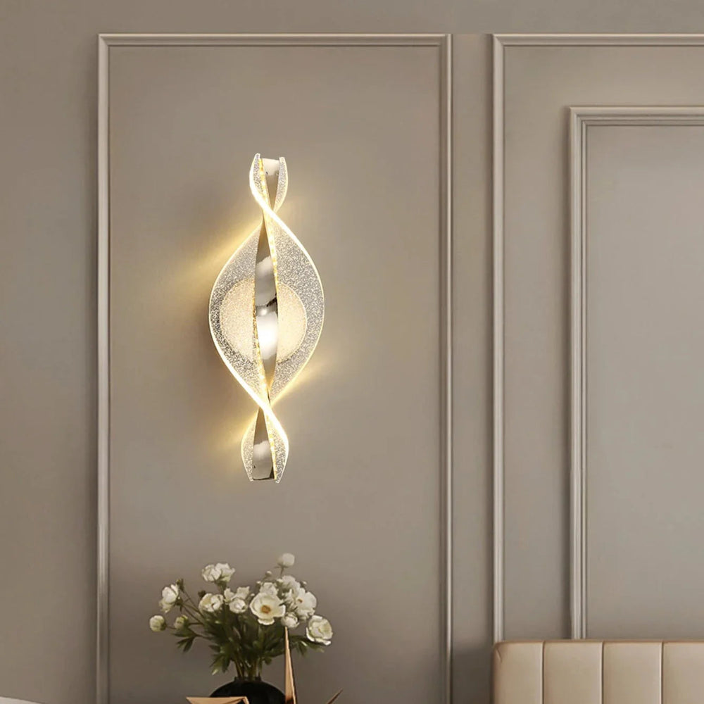 Decorative wall light fixture on a beige wall with a vase of flowers in the foreground.