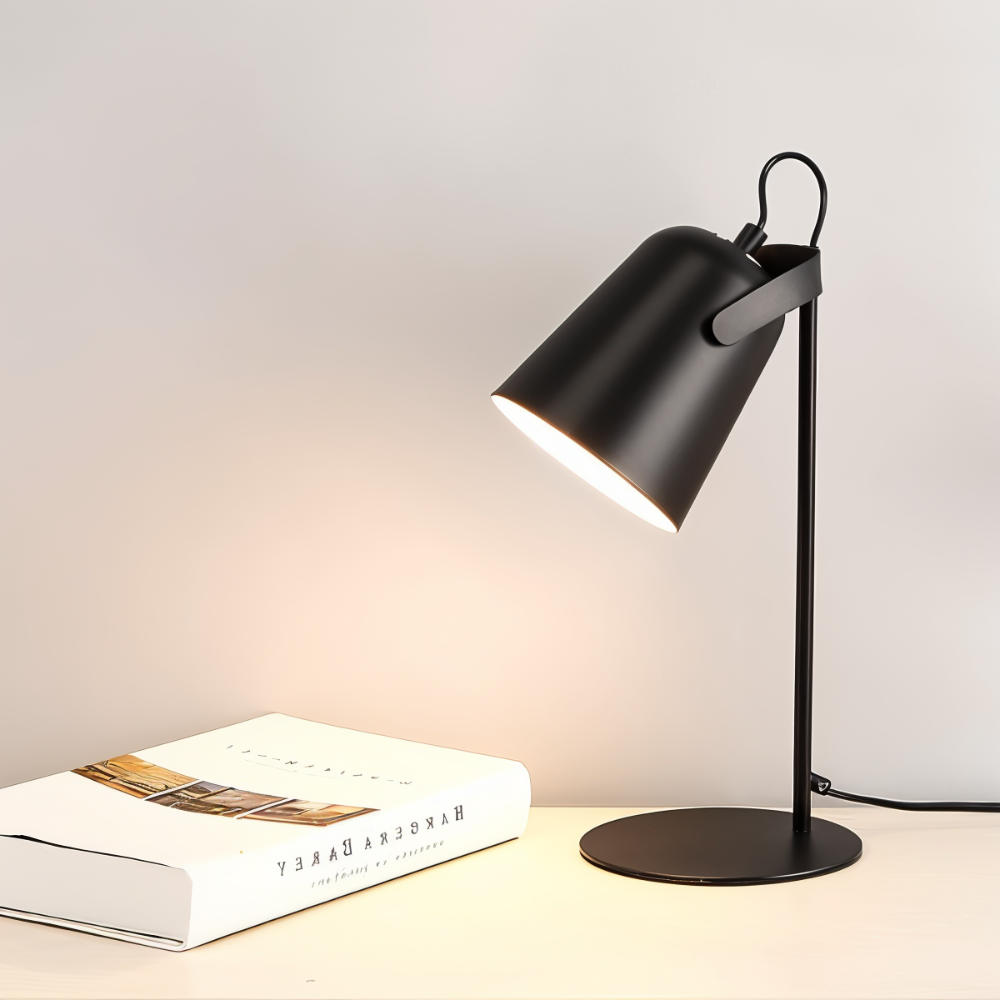 Black desk lamp on a surface with a book next to it