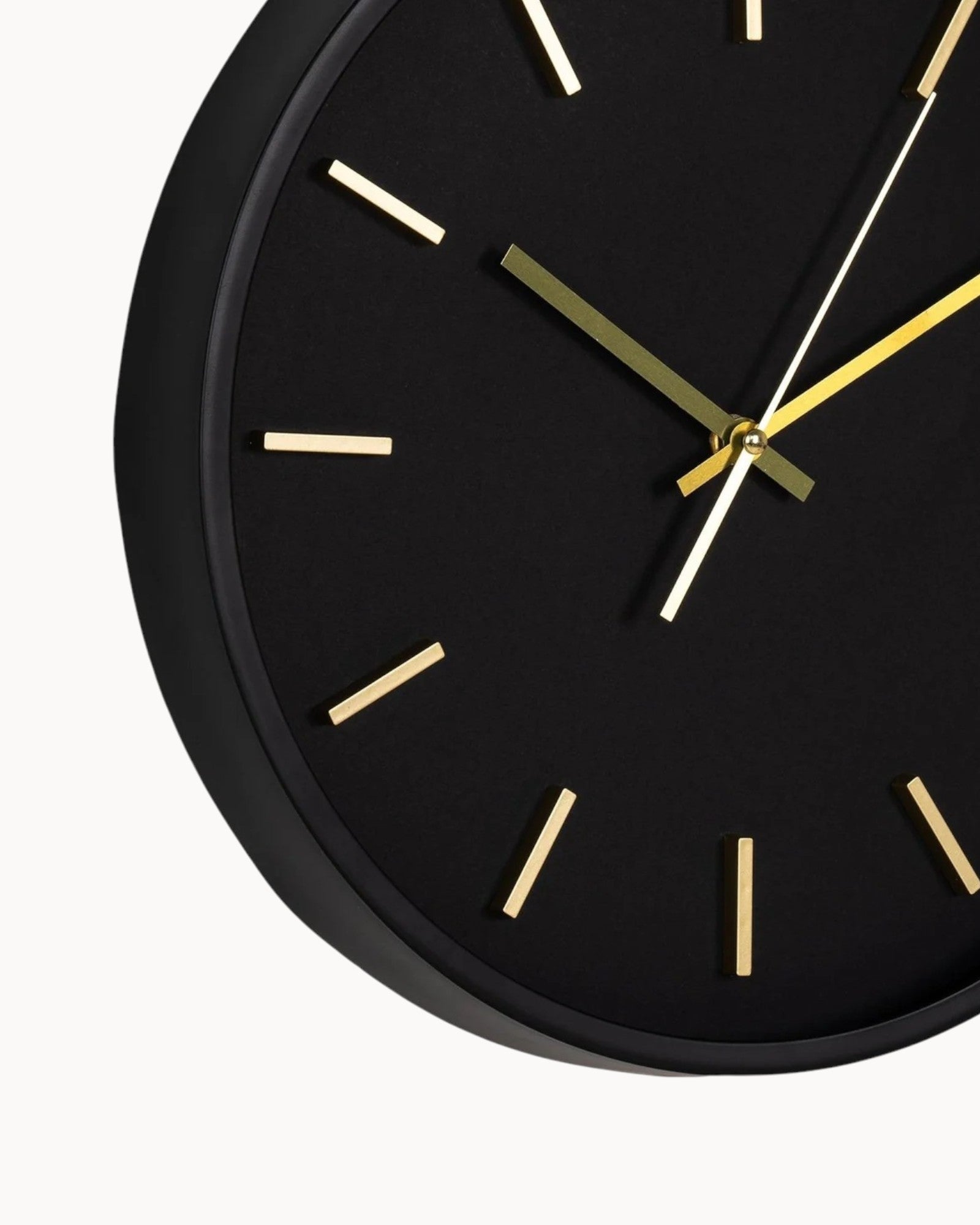 Black wall clock with gold hands on a white background