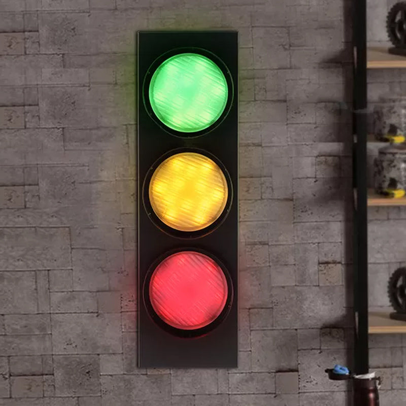Traffic light with green, yellow, and red lights on a stone wall background