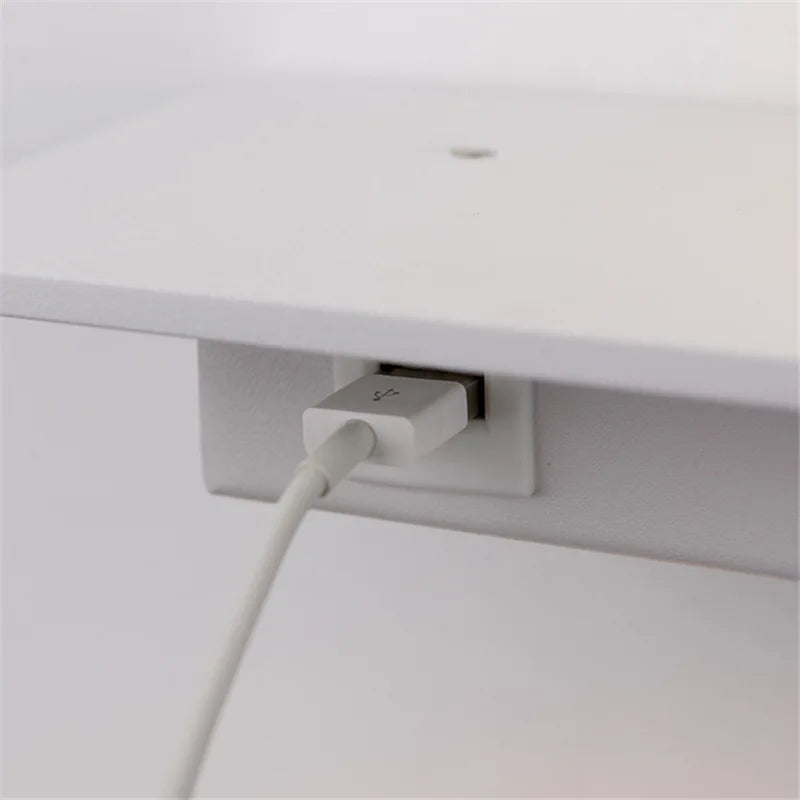 White USB cable plugged into a wall socket on a white background