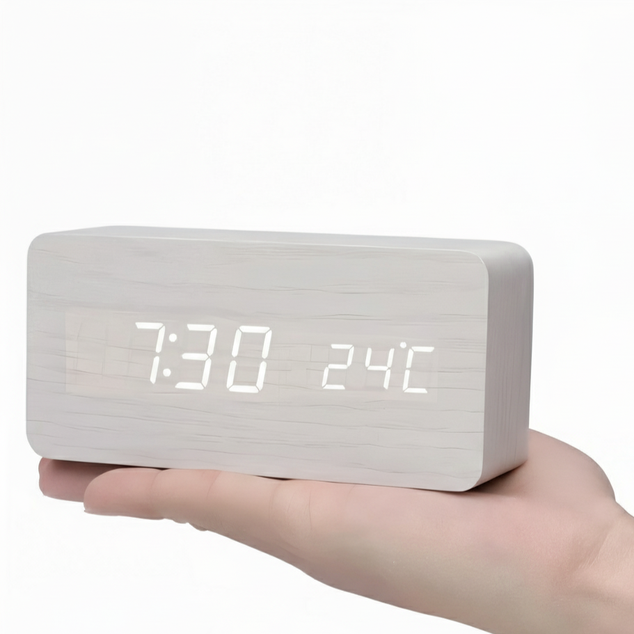 White digital clock with LED display held in a hand on a white background
