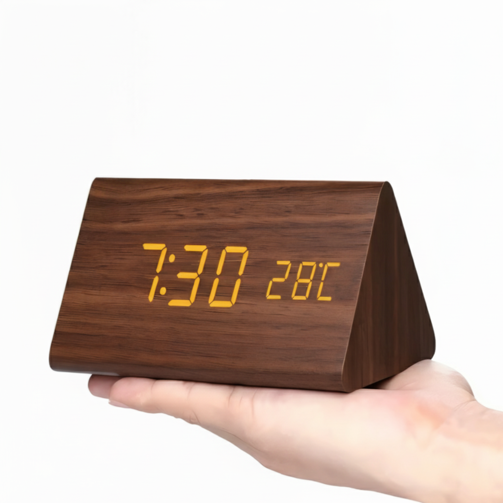 Wooden digital clock with orange LED display held in a hand against a white background