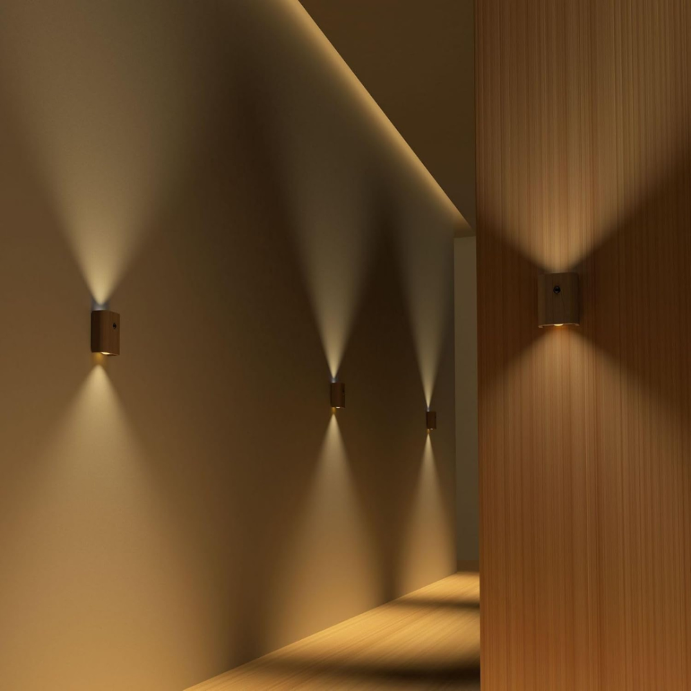 Wall-mounted lights casting shadows on a wall and wooden surface.