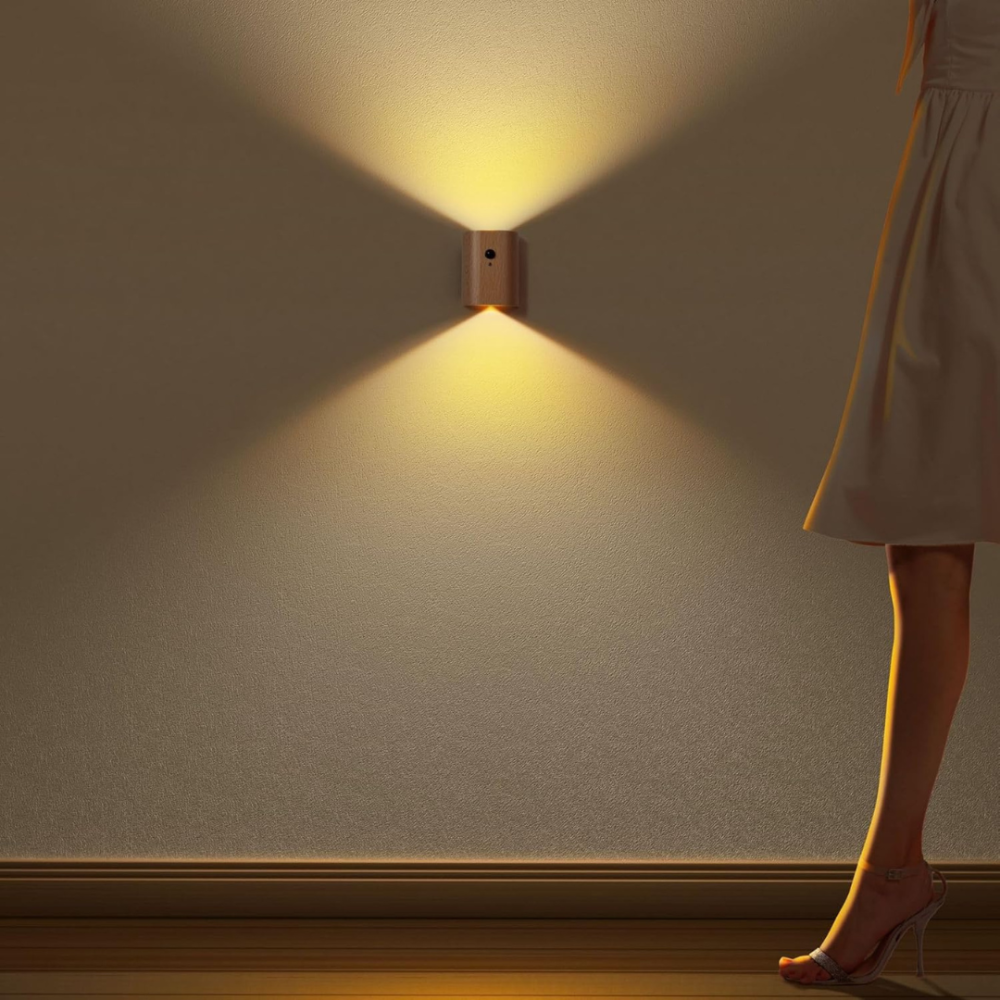 Wall-mounted light fixture casting a warm glow on a plain wall with a person's leg in a dress partially visible.