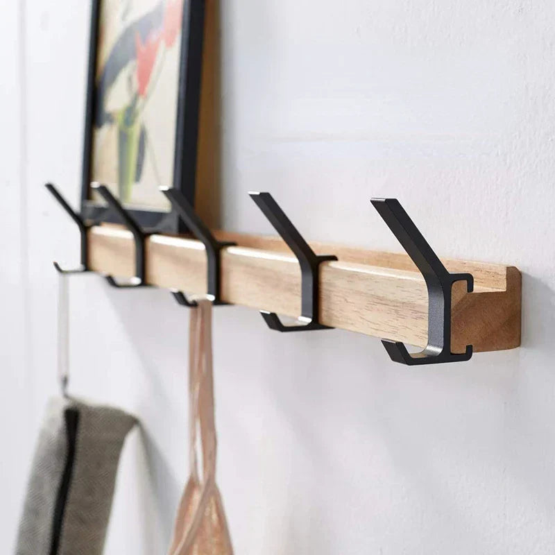 Wooden wall hook with black metal hooks on a white wall