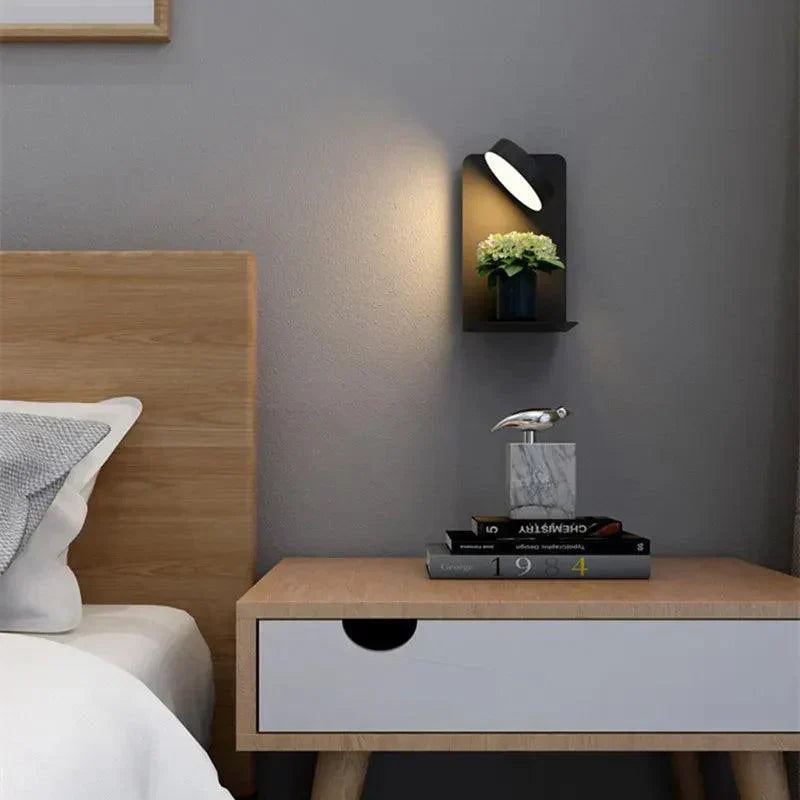 Modern bedroom with wooden nightstand, books, and decorative items against a gray wall.