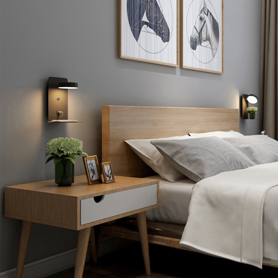 Modern bedroom with wooden bed and side table, featuring wall art and lighting.