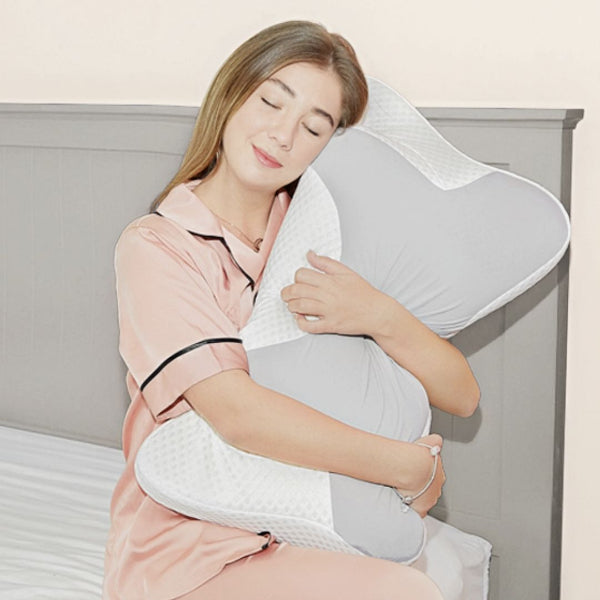 Woman holding a white pillow with a gray cover in a bedroom setting