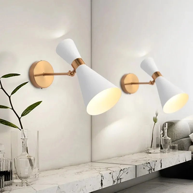 Two modern wall sconces with white shades and gold accents on a white wall.