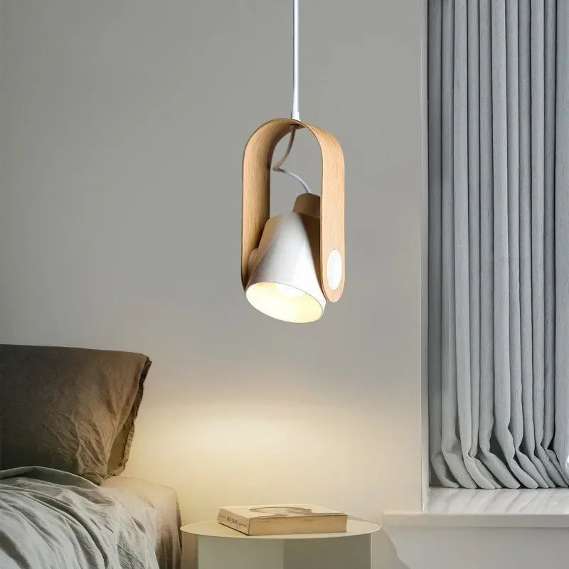 Modern pendant light hanging above a bed with a neutral color scheme.