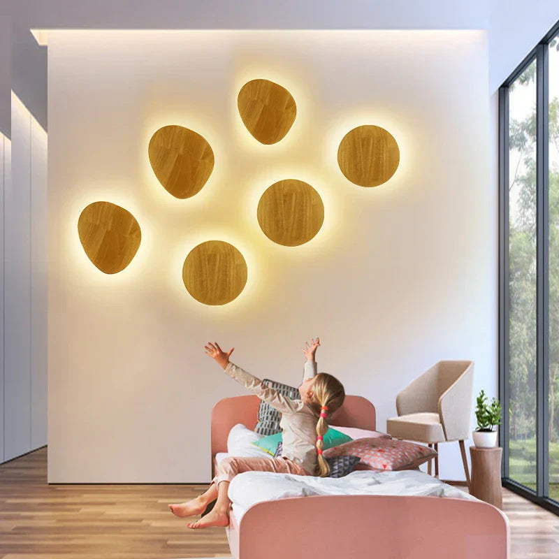 Children playing on a bed in a modern bedroom with wooden wall lights.
