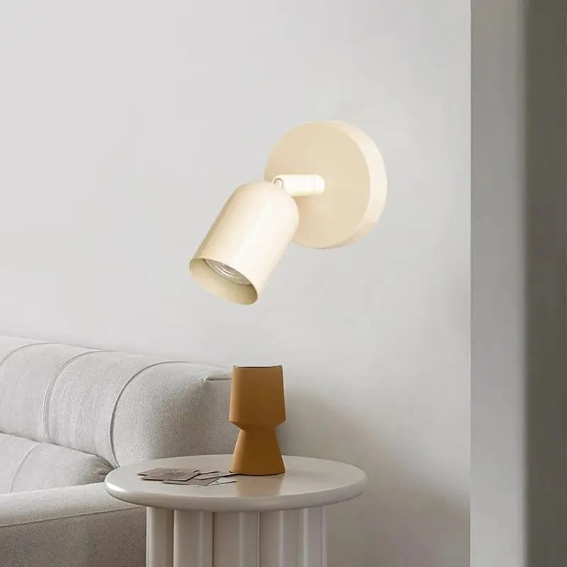 Modern wall lamp on a light gray wall with a small table and decorative item below.