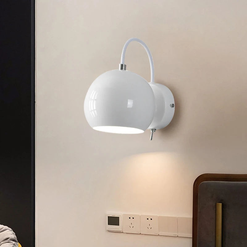 White wall-mounted lamp on a beige wall with a dark curtain and wooden furniture.