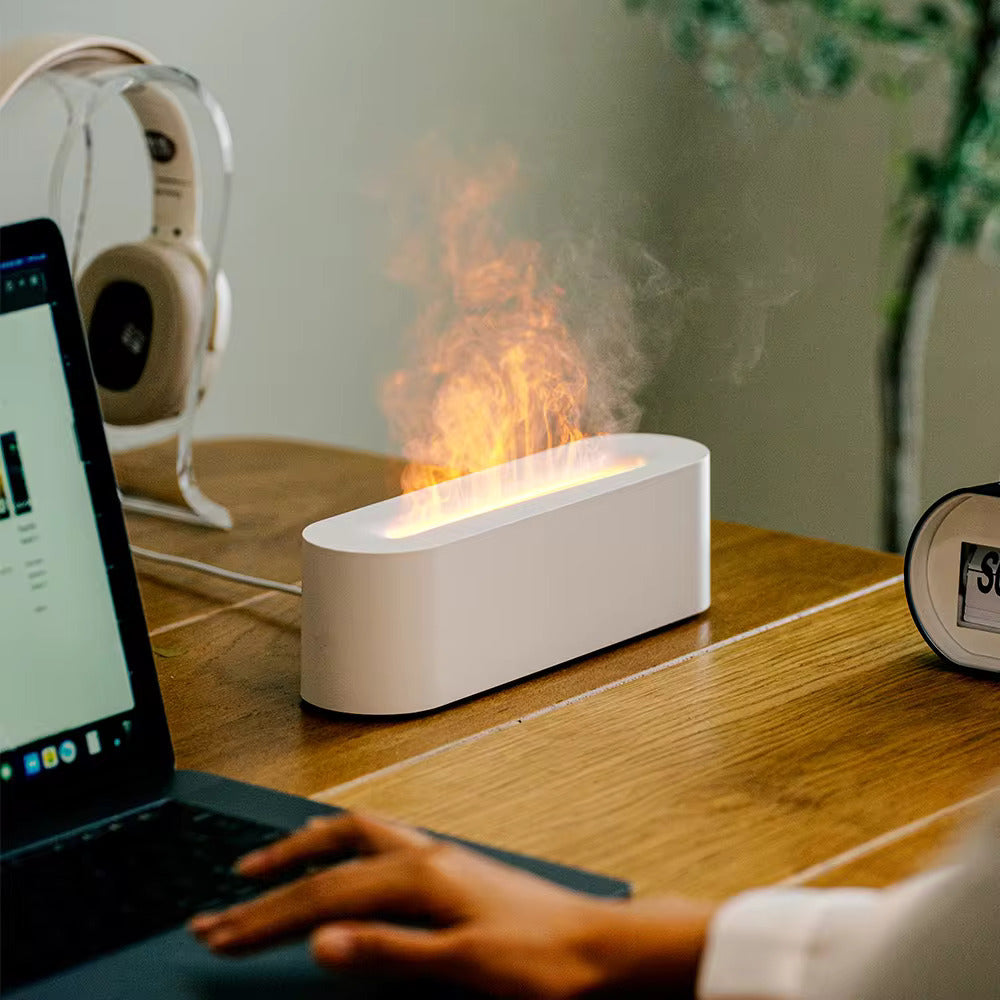 Laptop on a desk with a fire-themed lamp and headphones in the background
