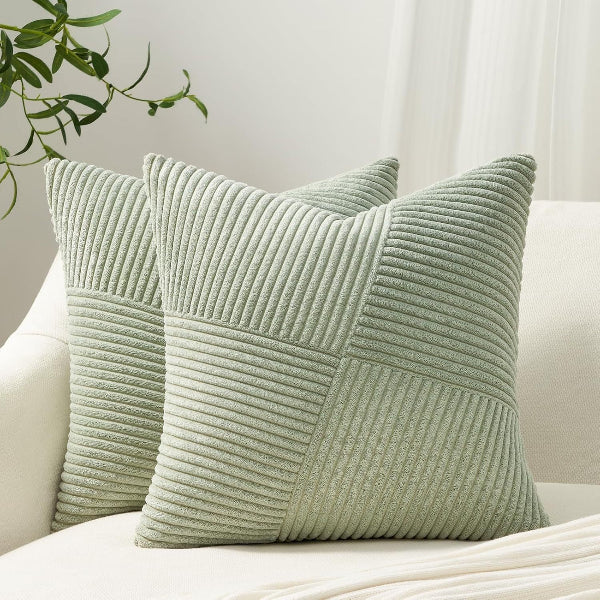 Two green textured pillows on a white sofa with a neutral background