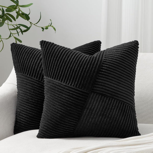 Three black textured pillows on a white sofa with a plant in the background