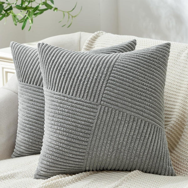 Gray textured pillows on a beige sofa with a blurred plant in the background