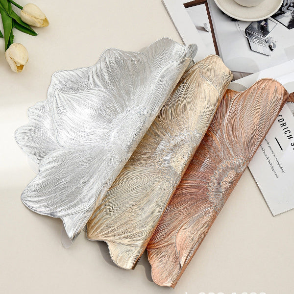 Three decorative platters with leaf-like designs in silver, gold, and rose gold on a light surface.