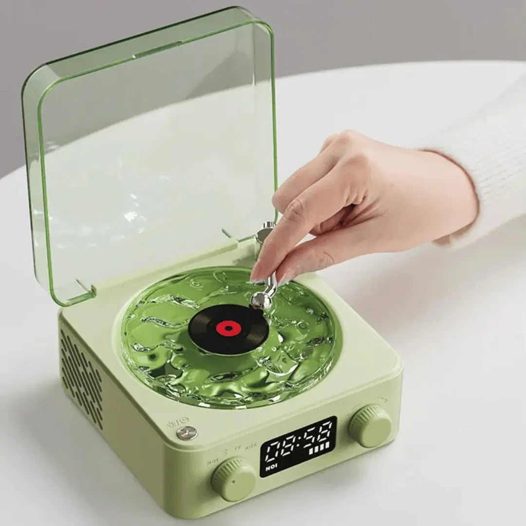Green record player with a hand placing a vinyl record on it, on a white surface.