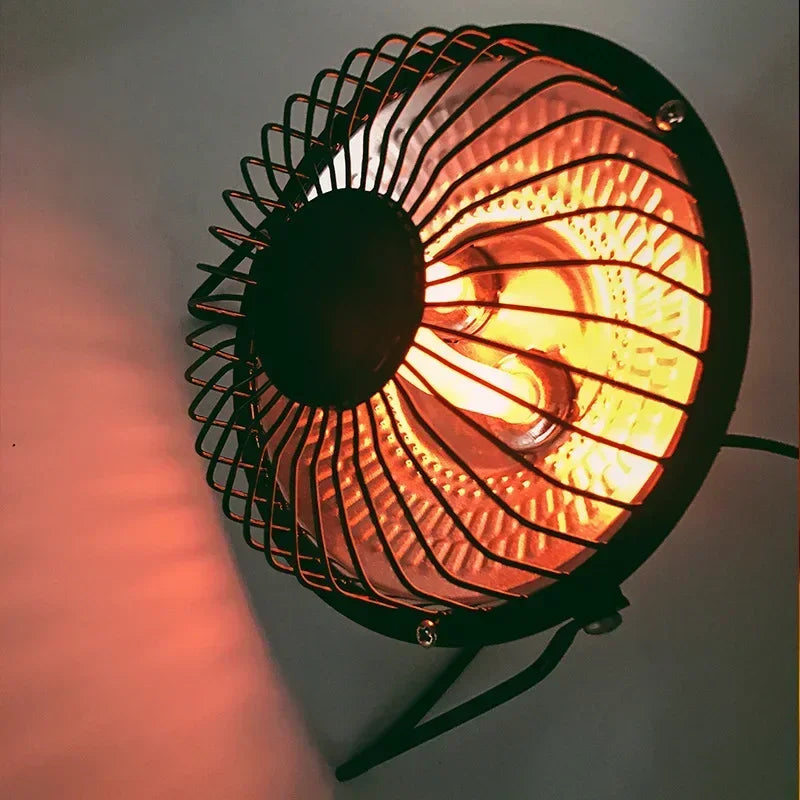 Small round electric heater with glowing light on a dark background