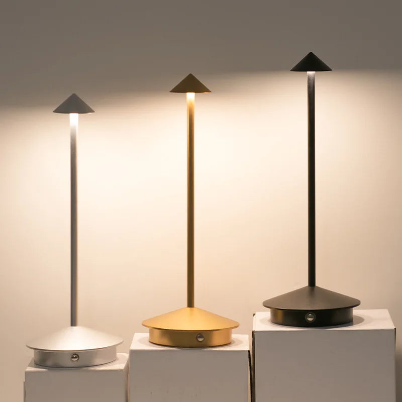 Three modern table lamps on white pedestals against a neutral background