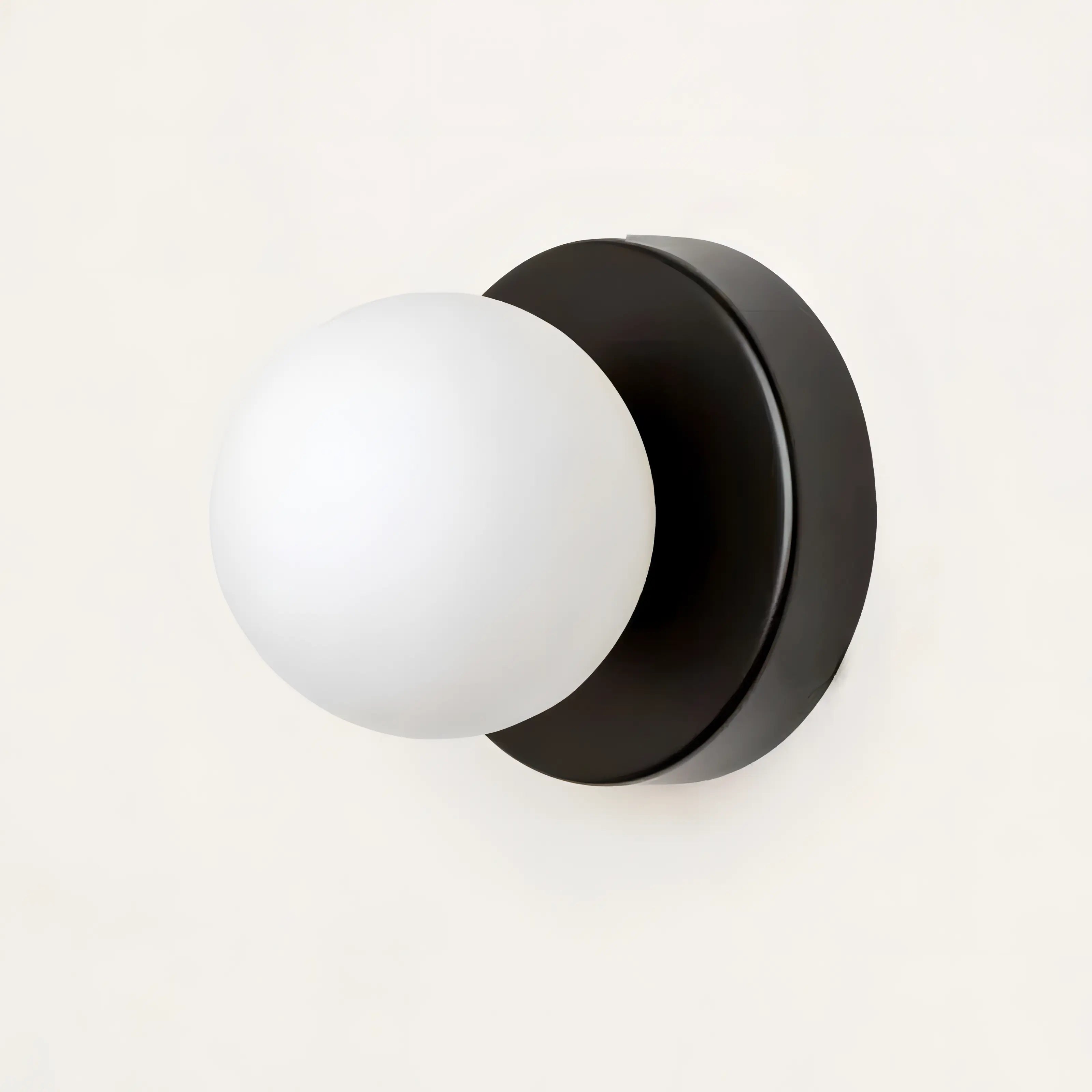Wall sconce with white globe light and black finish on a white background