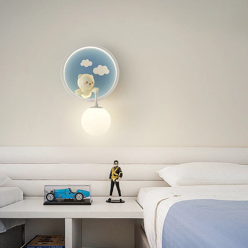 Modern bedroom with a wall lamp featuring a teddy bear design, a bed, and decorative items on a nightstand.