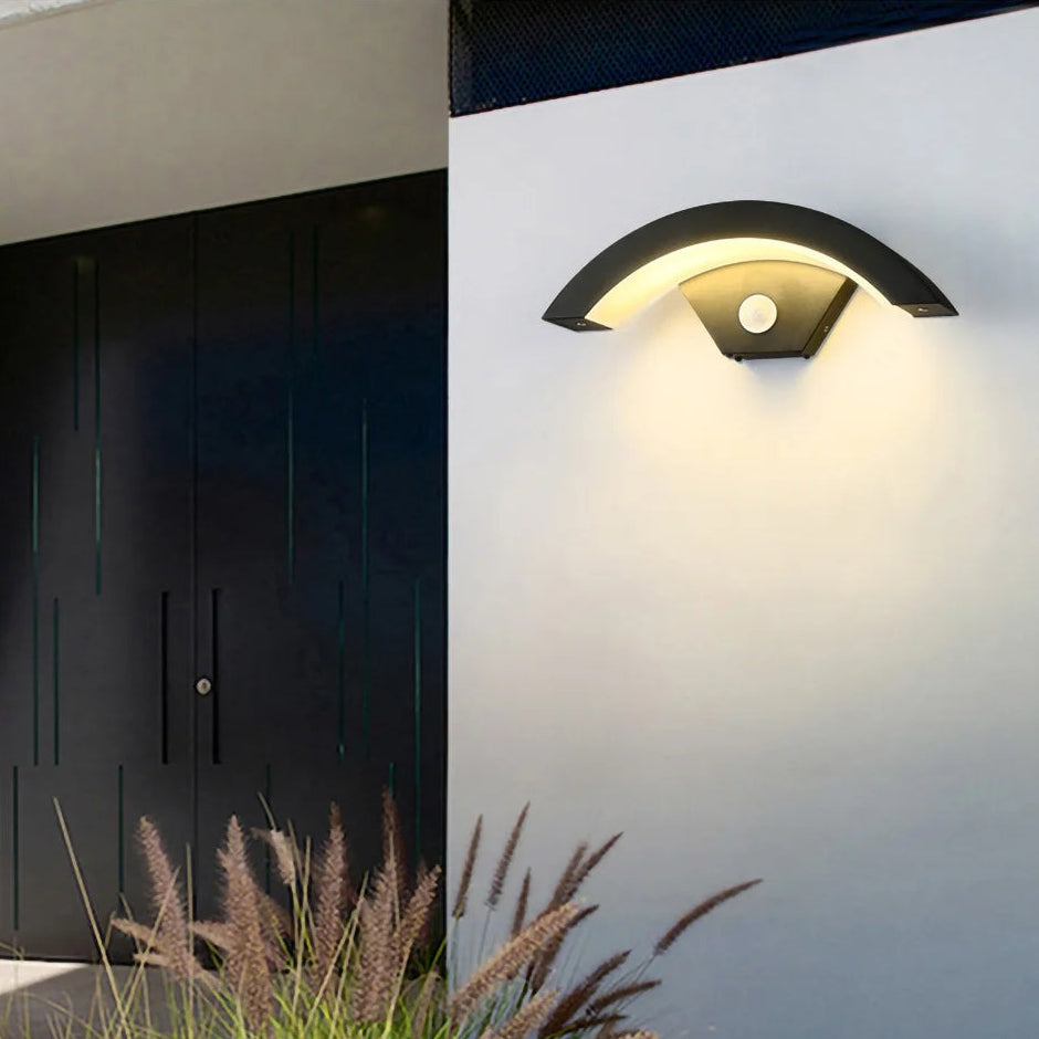 Modern outdoor wall light fixture on a white wall with grass in the foreground.