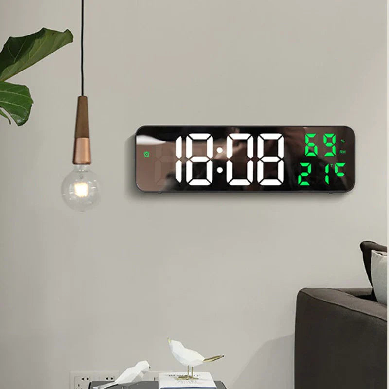 Digital wall clock with large LED display on a light gray wall.