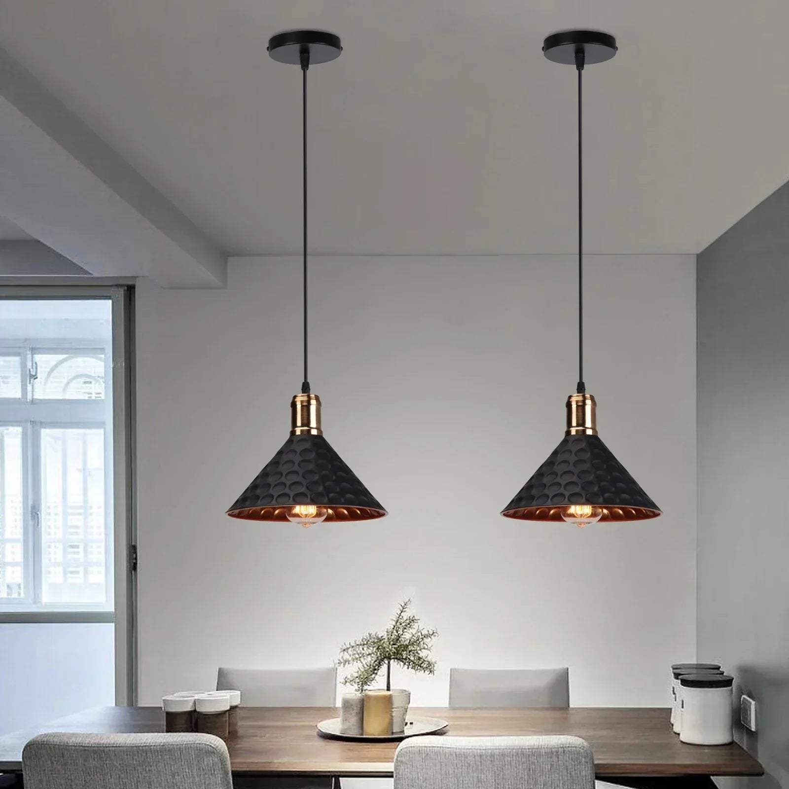 Two black pendant lights hanging above a dining table in a modern room.
