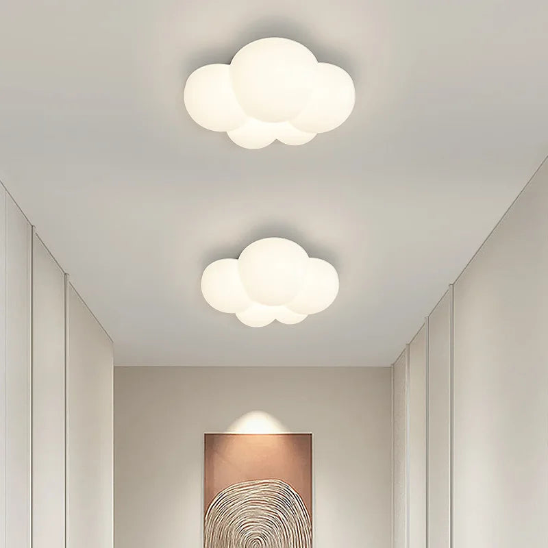 Two cloud-shaped ceiling lights in a room with neutral walls and a wall sconce.