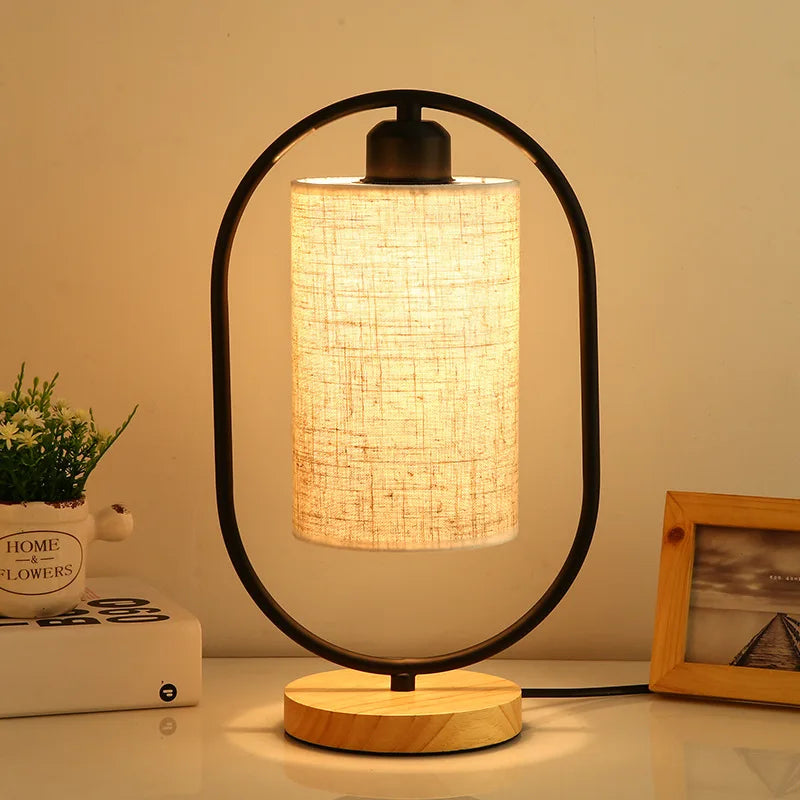Table lamp with a woven shade on a wooden base, emitting warm light.