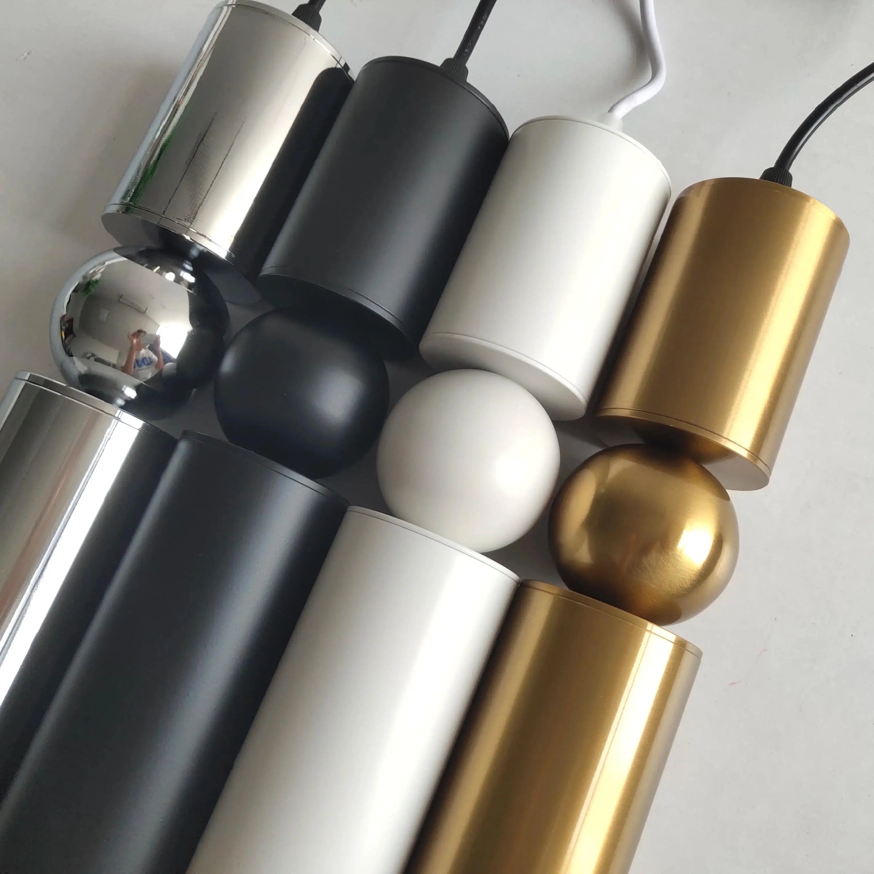 Close-up view of modern pendant light fixtures in metallic silver, matte black, white, and gold finishes.