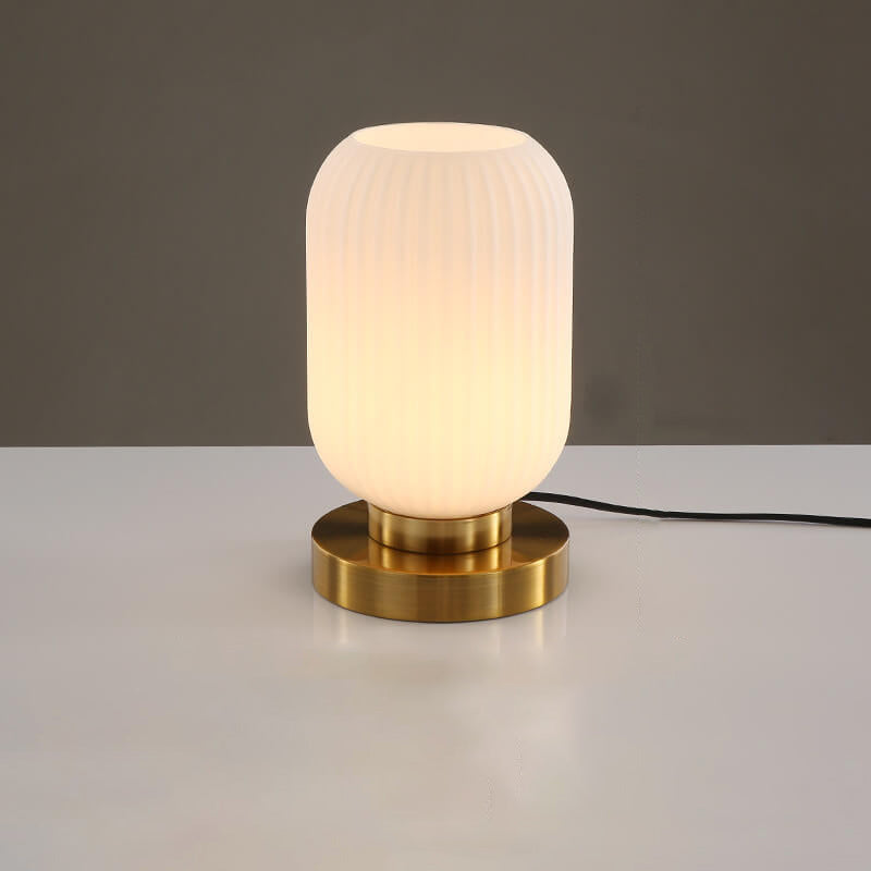 Table lamp with a ribbed glass shade and brass base on a neutral background