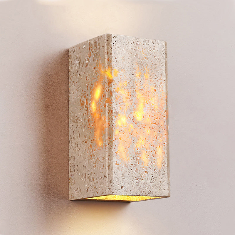 Cement wall sconce with a warm glow on a neutral background