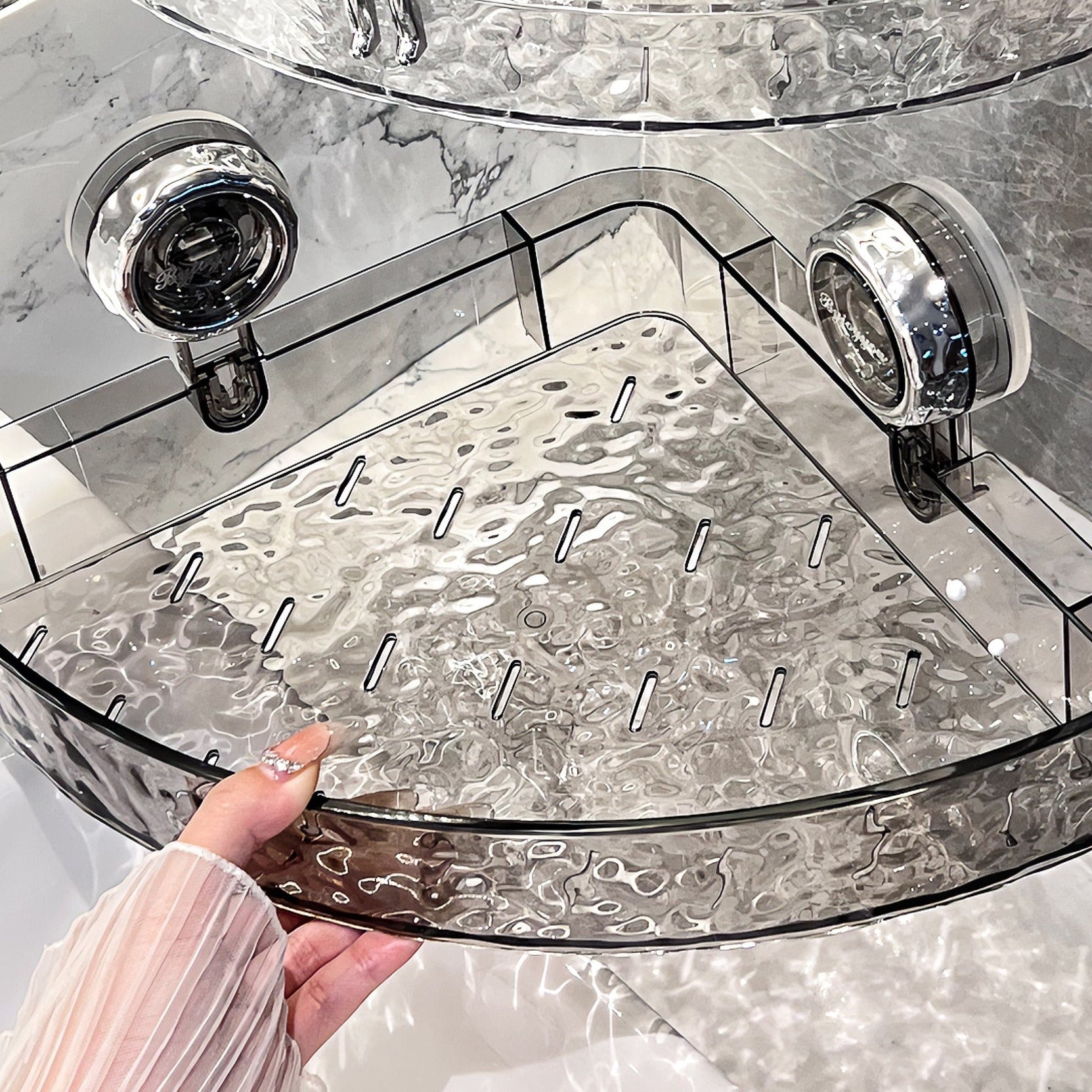 Clear glass tray with decorative pattern held by a hand on a marble surface
