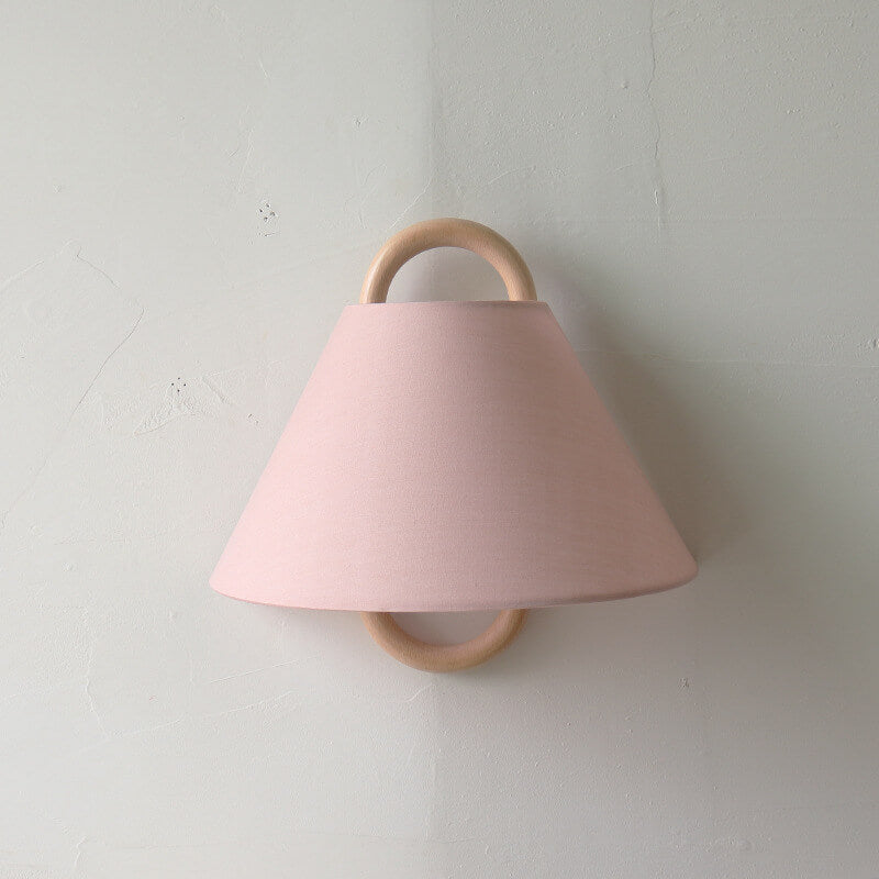 Pink wall light fixture with wooden accents on a plain wall