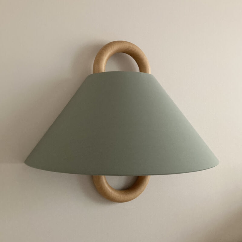 Wall-mounted lamp with green shade and wooden accents on a beige wall