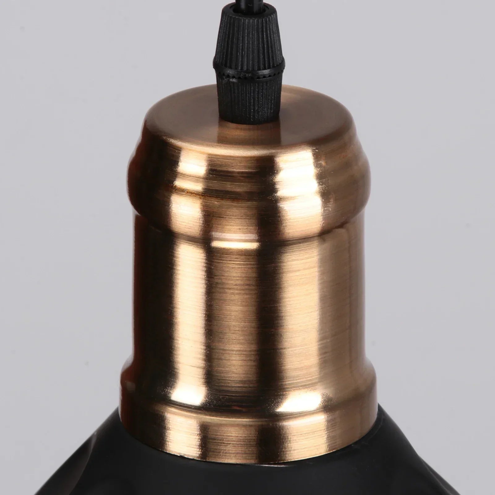 Close-up of a brass lampshade with a black base on a gray background