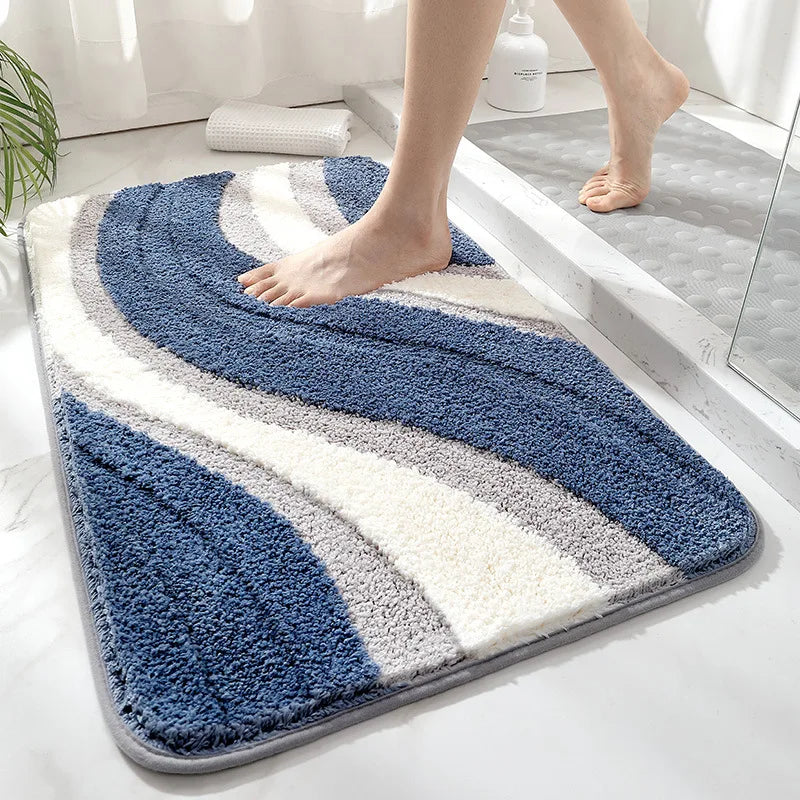 Blue and white striped bath mat on a bathroom floor with a person stepping onto it.
