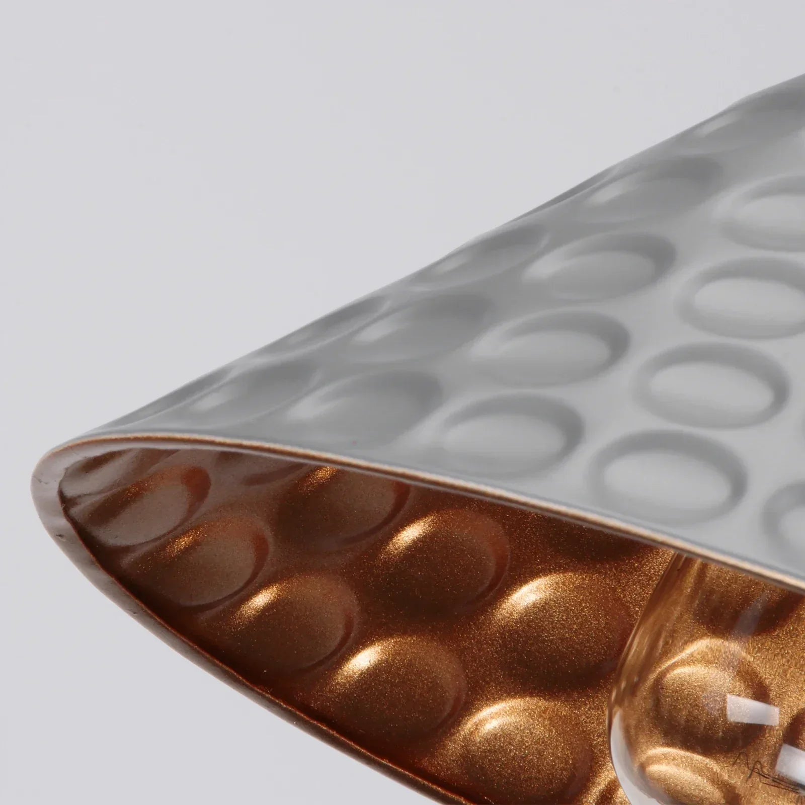 Close-up of a textured container with a metallic interior on a light gray background