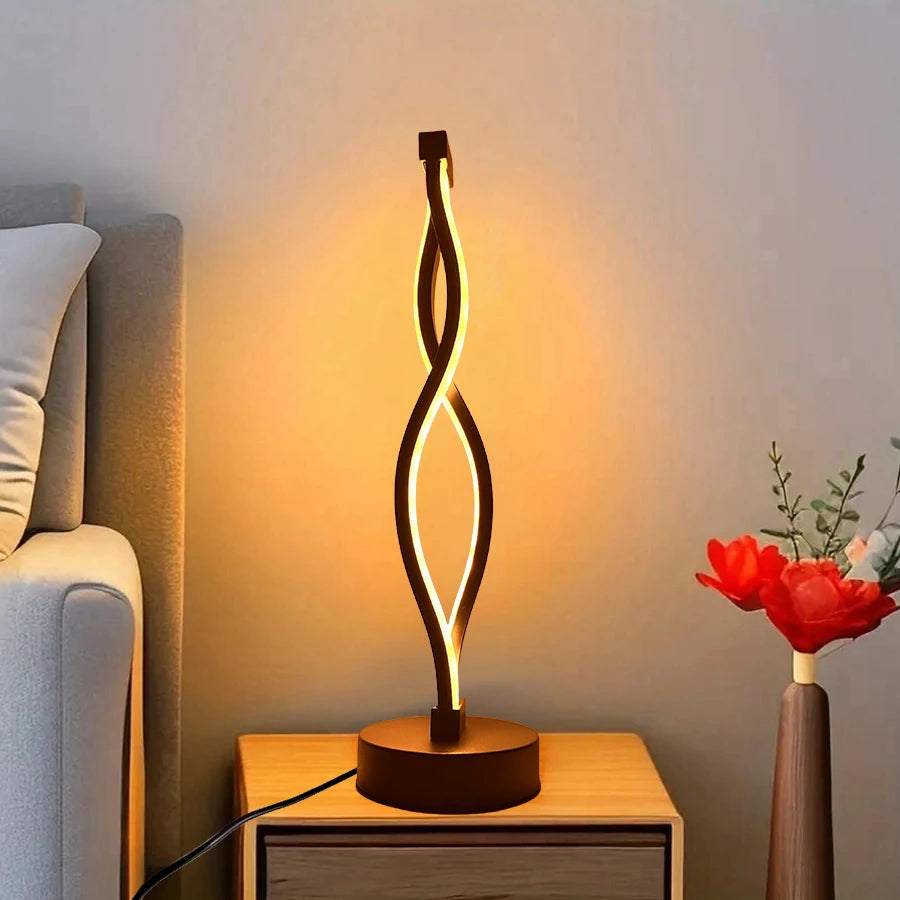Decorative table lamp on a wooden side table with a soft glow, next to a sofa and a vase with red flowers.