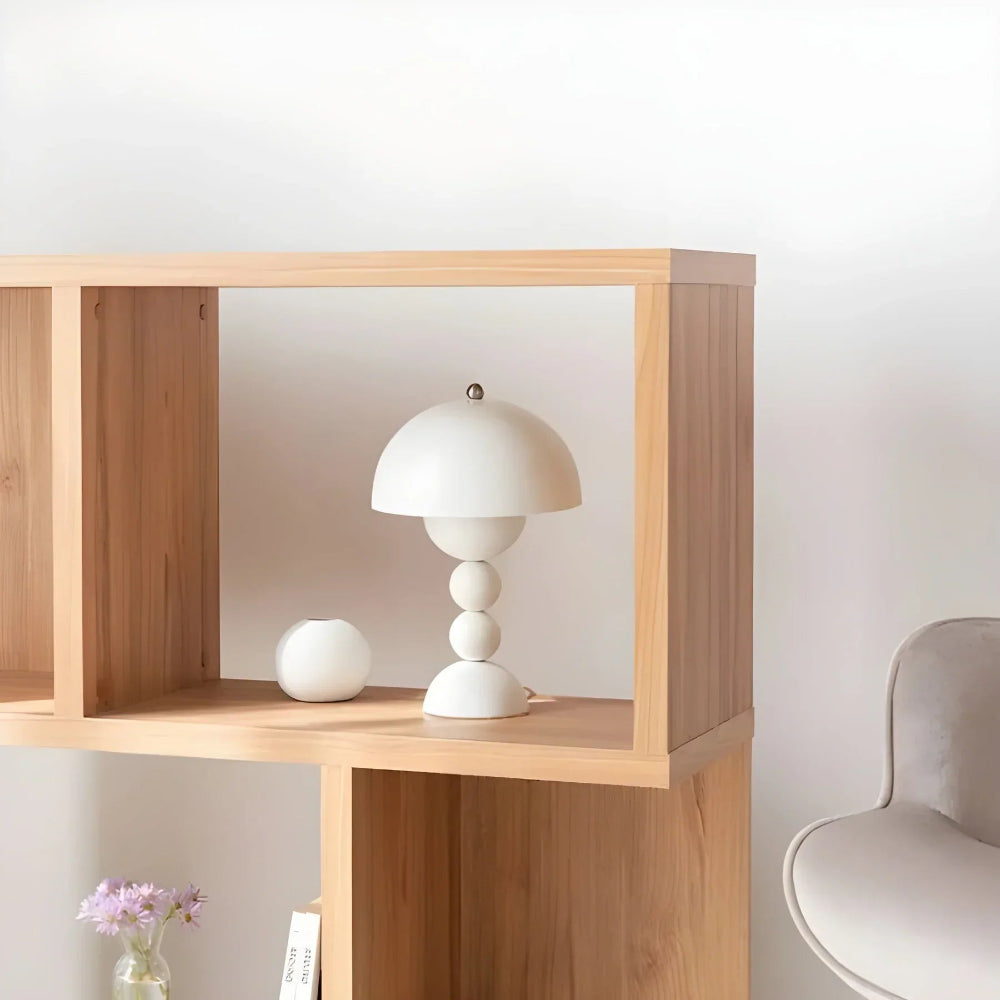 Wooden shelf with a white lamp and decorative ball against a light wall.