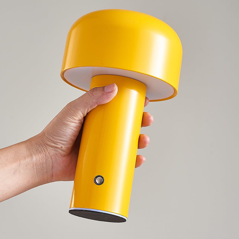 Yellow portable lamp held by a hand against a gray background