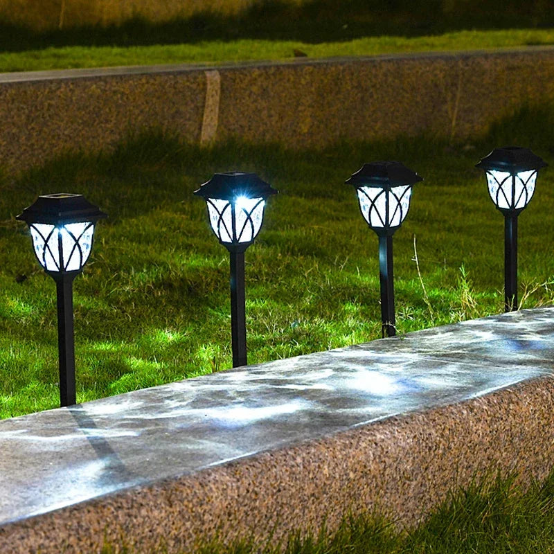 Four solar-powered garden lights on a grassy area with a concrete path.